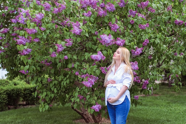 Foto belly ragazza incinta nel giardino di lilac