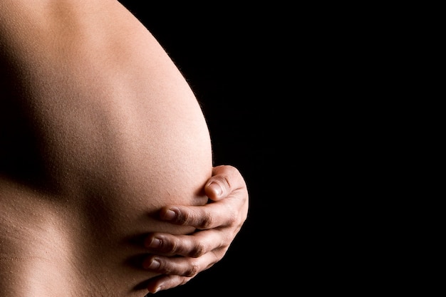 Pancia della donna incinta contro uno sfondo nero