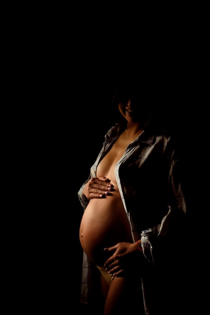 Belly of pregnant woman over dark 