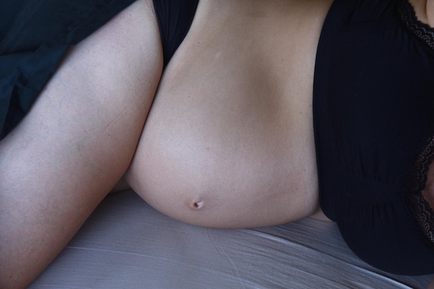 Belly of a pregnant woman lying on the bed