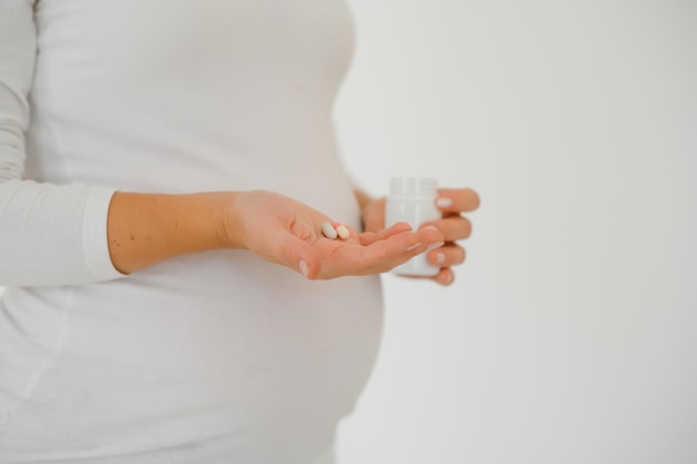 Belly of pregnant woman and vitamin pills in the hand