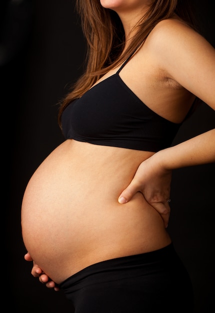 Photo belly of a pregnant woman with lower back pain.