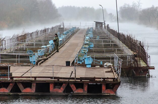 Beloozersk Belarus2018年11月11日魚産業の男性が魚に餌をやったり繁殖させたりする秋の寒い日霧が水魚養殖場に広がる