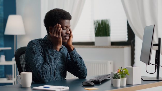 Benadrukkende Afro-Amerikaanse man met grote hoofdpijnpijn die lijdt aan migraine die over zijn slapen wrijft