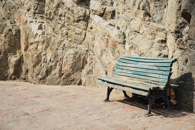 Bench on the background of a rock in the park an empty bench the idea of loneliness and loss empty space for text