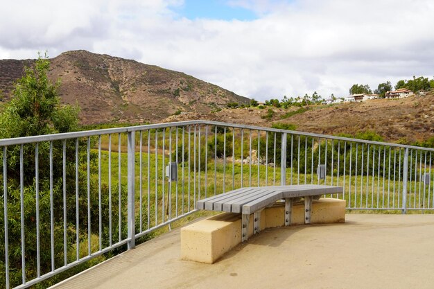 A bench on a balcony with mountains in the background.