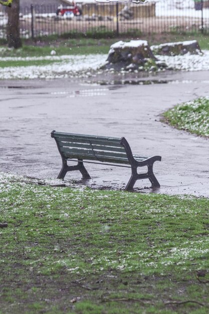 a bench is in the rain and the grass is wet