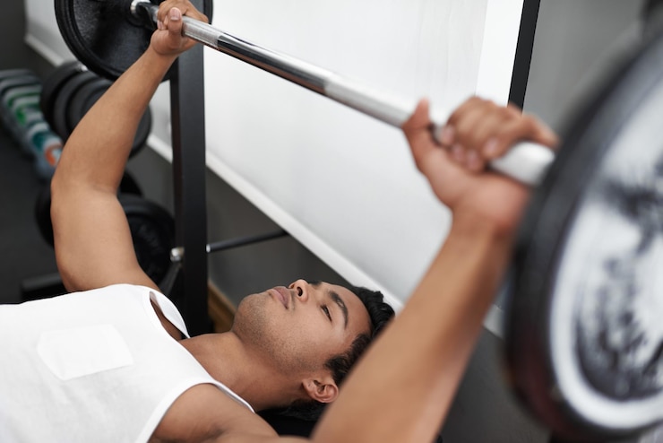 Photo bench press and man at gym for exercise workout and body building in mexico healthy person and weightlifting challenge for strong muscle fitness or progress in training arms with barbell in club