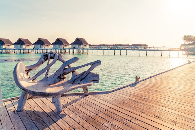 Bench with tropical Maldives resort hotel and sea