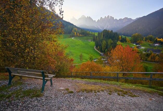 Bench with view on Santa Maddalena St Magdalena village with Dolomites mountains on background Val di Funes valley Italy Europe