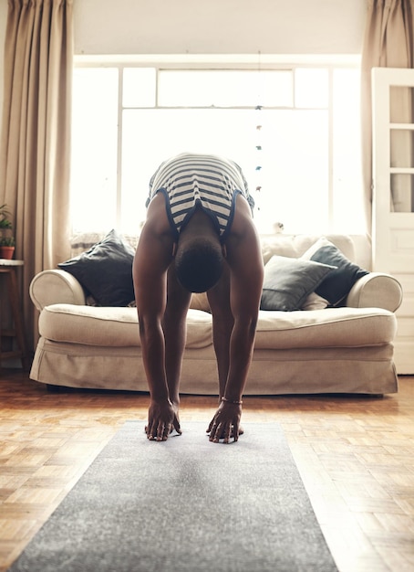 Bend down and feel the stretch Shot of a sporty young man touching his feet while exercising at home