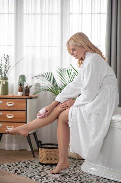 Benen massage. Vrouw in wit haar benen masseren met massageapparaat
