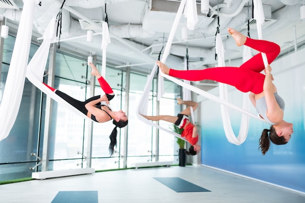 Foto benen strekken zich uit. actieve en fitte vrouwen en mannen die hun benen strekken terwijl ze vliegende yoga doen