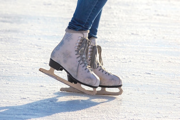 Foto benen van een meisje in spijkerbroek en witte schaatsen op een ijsbaan. hobby's en vrije tijd. wintersport