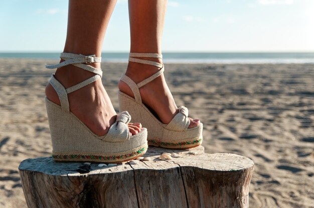 Benen van een vrouw in elegante witte wiggen op het strand