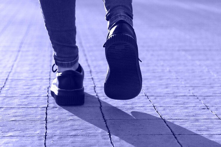 Benen van een wandelend meisje in spijkerbroek, de trendkleur van 2022 is erg peri