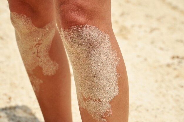 Benen van jonge vrouw in het zand op een tropisch strand