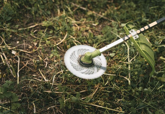 Foto benzine trimmer hoofd op groen gras. rond trimmerblad.