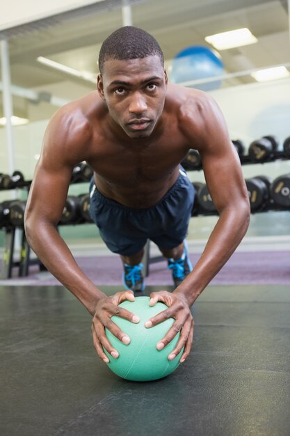 Bepaalde man doet push-ups met bal in de sportschool