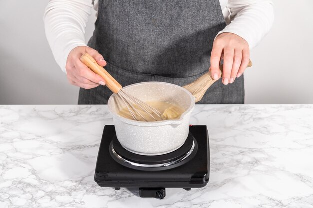 Bereid toffeeglazuur in een kleine sauspan boven een elektrisch fornuis.