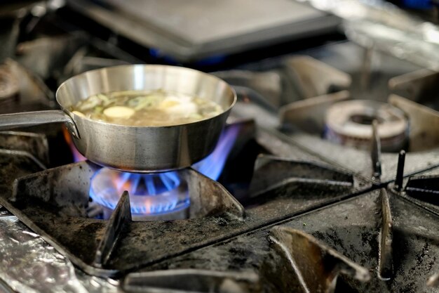 Bereiding van soep in zilveren pan op gas