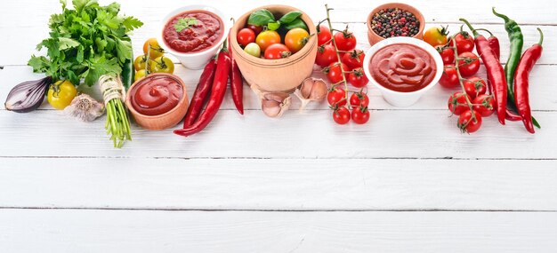 Bereiding van tomatensauzen en smaakmakers Kersentomaten, specerijen, chilipepers Bovenaanzicht Op een witte houten achtergrond Gratis kopieerruimte