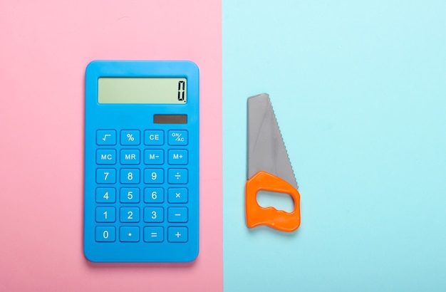 Berekening van de kosten voor het bouwen van een huis of huishoudelijk werk. Rekenmachine en speelgoed zag op blauw-roze pastel achtergrond. Bovenaanzicht