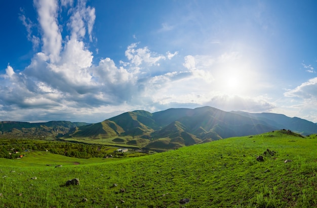 Berg groene heuvel tegen blauwe bewolkte hemel met de zon helder schijnt. Natuur landschap. Reizen achtergrond. Vakantie, wandelen, sport, recreatie. Schoonheidswereld verkennen: bergen van de Kaukasus, Georgië