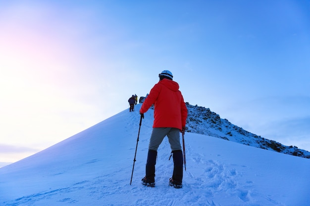 Bergbeklimmer bereikt de top van een besneeuwde berg op een zonnige winterdag