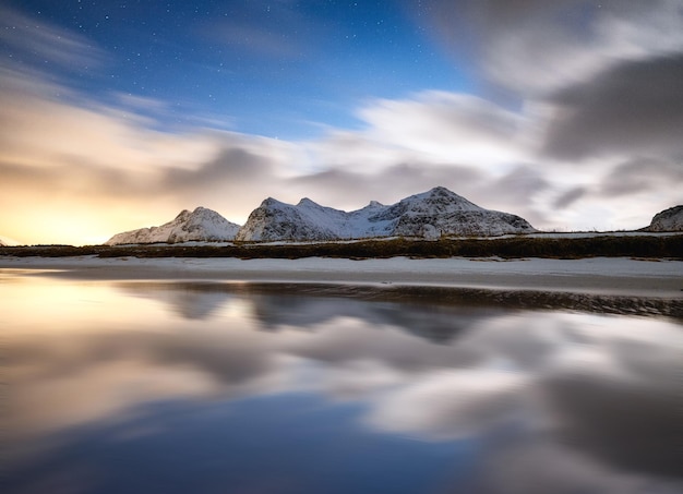 Bergen en reflecties op het water 's nachts Winterlandschap De lucht met sterren en wolken in beweging Natuur als achtergrond Noorwegen reizen