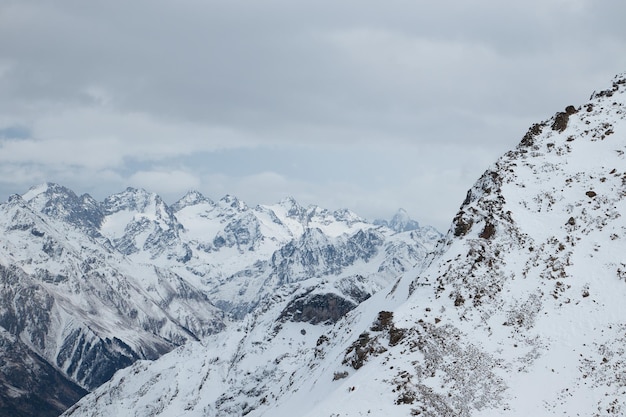 Bergen in de sneeuw winter berglandschap sombere hemel en mist rotsen op de voorgrond