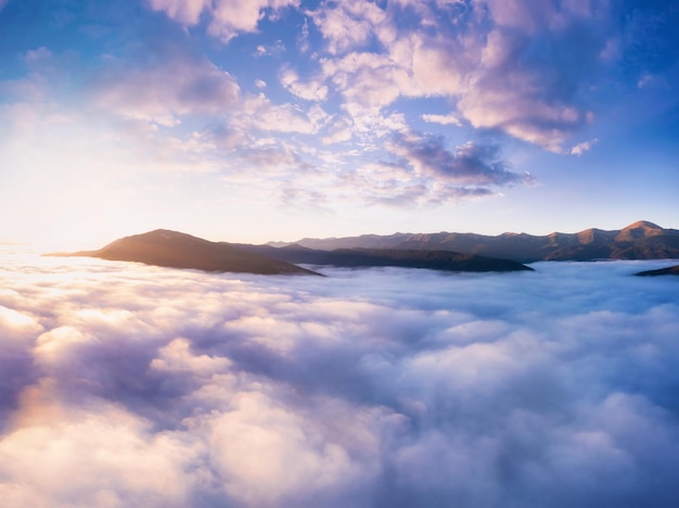 Bergen in lage wolken bij ochtendzonsopgang Prachtig landschap met bergtoppen in mist