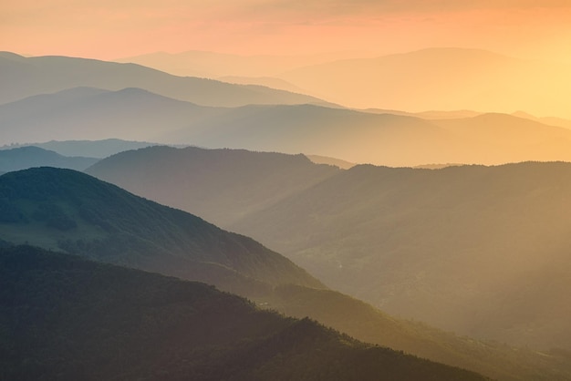 Bergen tijdens zonsondergang Lijnen van berghellingen tijdens zonsondergang Mist in de bergen Zonlicht Natuurlijk landschap in de zomer