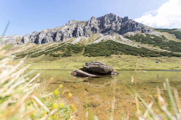 Berglandschap Meer met helder water op de voorgrond ruige bergen op de achtergrond