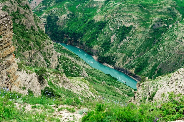 Berglandschap met een diepe kloof met een blauwe rivier waarlangs een motorboot vaart