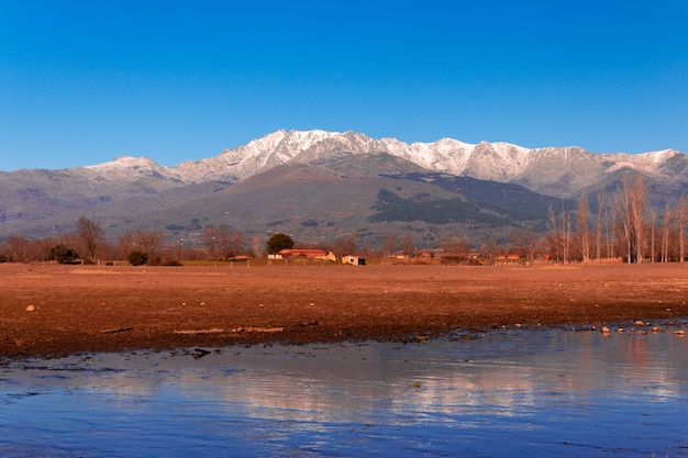 Berglandschap met sneeuw op de toppen weerspiegeld in het water van een meer Gredos Mountain