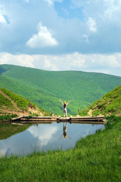 Bergmeer met een brug waarop een toeristisch meisje staat en het berglandschap bewondert