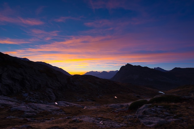 Bergsilhouet en overweldigende hemel met maan bij zonsondergang