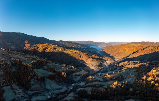 Bergtoppen bedekt met kleurrijke bomen bij zonsondergang