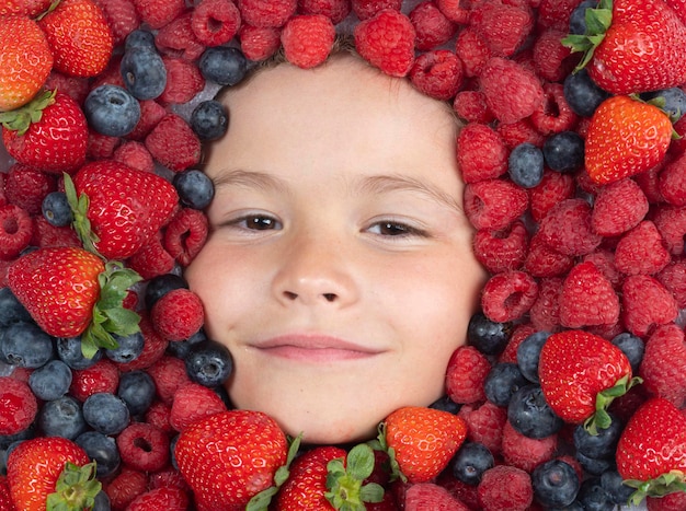 Berrie set Aardbeien, bosbessen, frambozen, bramen, achtergrond op het gezicht van het kind Gezonde kinderen eten Het gezicht van de kinderen met fruit en bessen