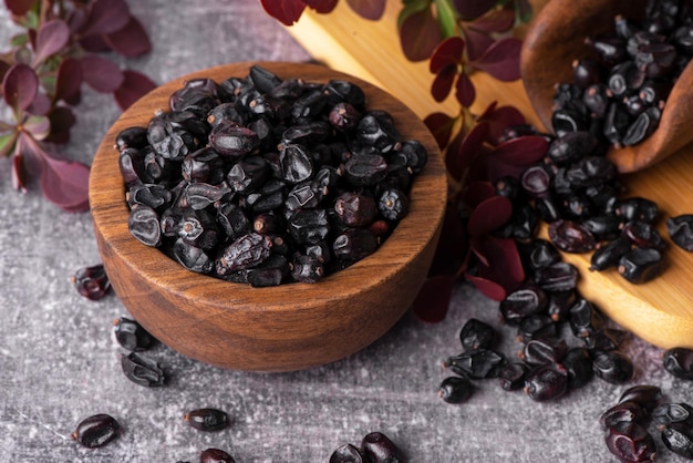 Berries of black barberry in wooden bowl and spoon Spice barberry blue Dry berries of barberries