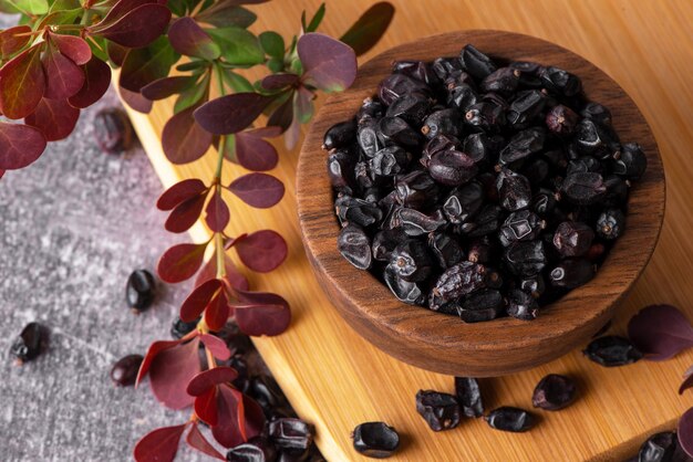 Berries of black barberry in wooden bowl and spoon Spice barberry blue Dry berries of barberries