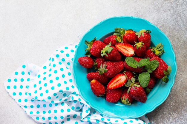 Photo berries of fresh strawberries in a blue ceramic plate on a gray stone or slate