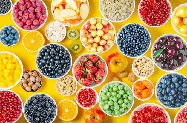 Berries fruits and nuts on a yellow background Vegetarian food