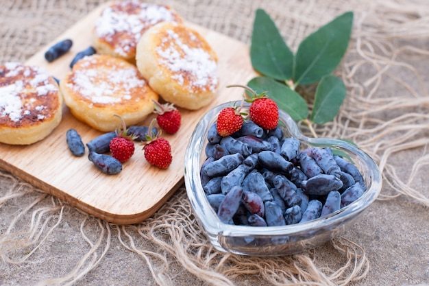 Photo berries of honeysuckle and pancakes on a concrete surface