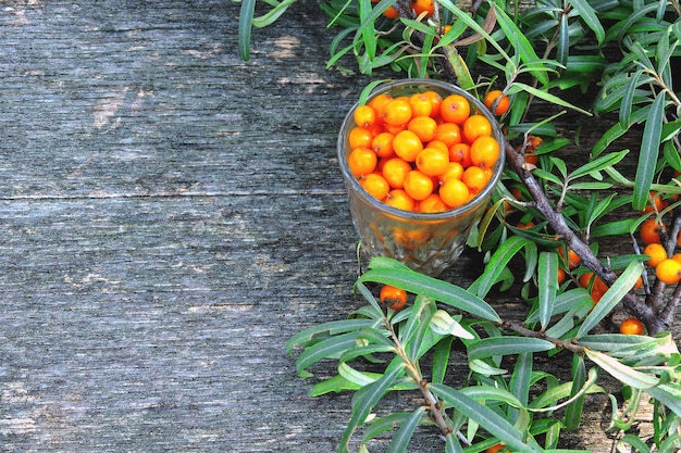 Berries and leaves of sea-buckthorn on a wooden background. The harvest of sea-buckthorn.