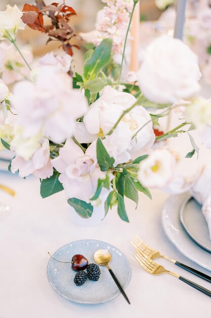 写真 花束の隣のセットテーブルの上に茶匙を立てた皿のベリー