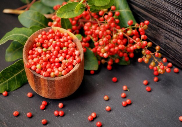 Berries of pink Brazilian pepper tree in a wooden bowl branches of Schinus terebinthifolia