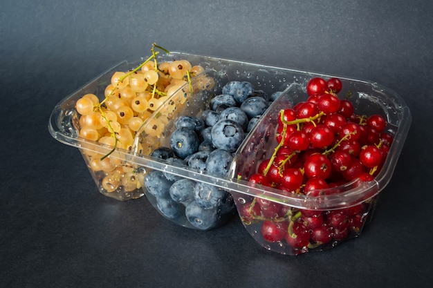 Berries of red and white currants and blueberries in plastic packaging.