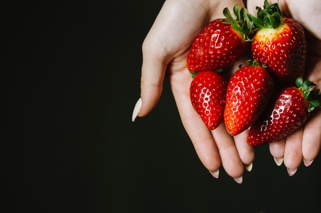 Berries of ripe red strawberries in women's hands closeup